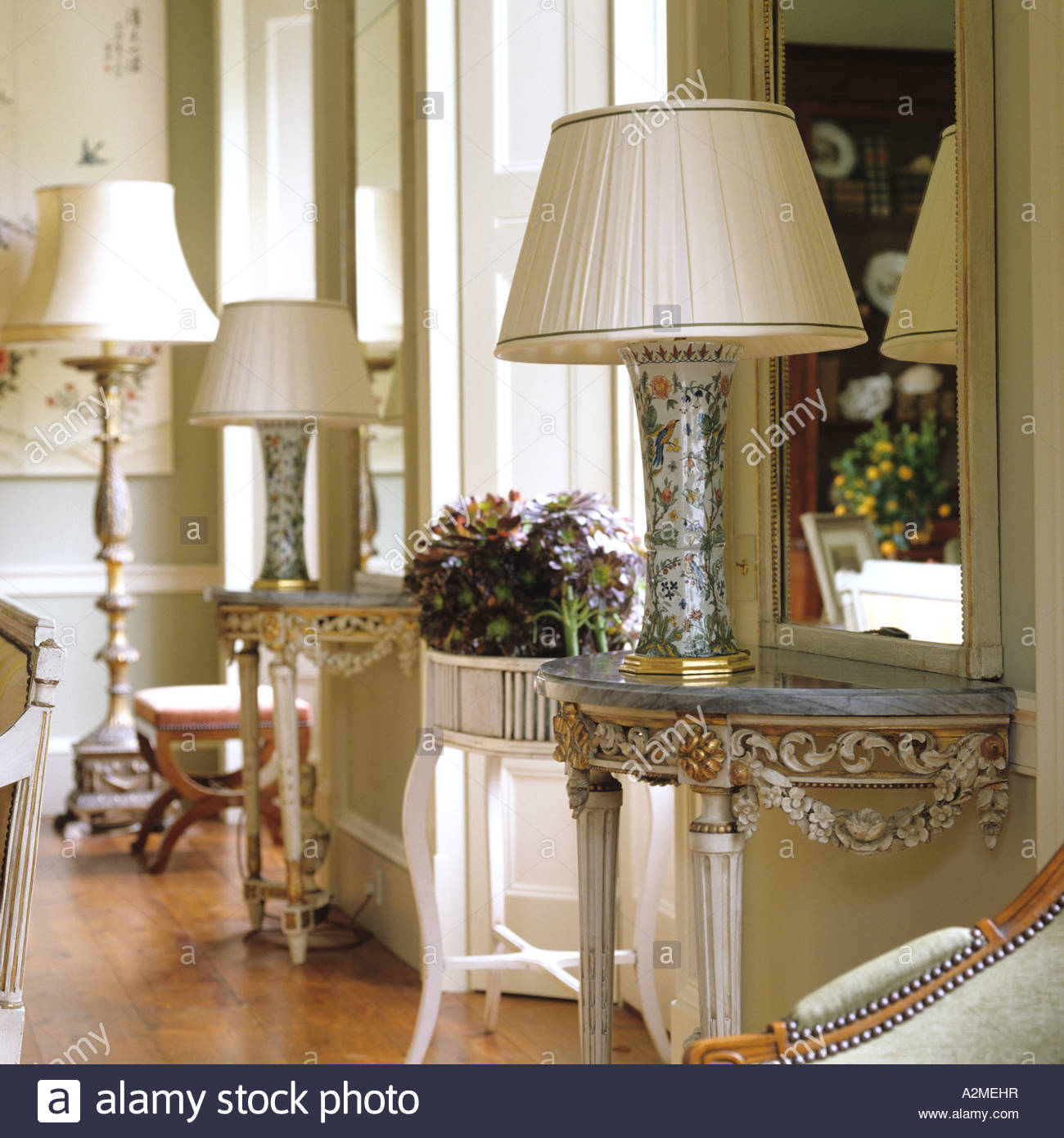country house lighting marble topped console tables with lamps in drawing room of english country GTKOJTG