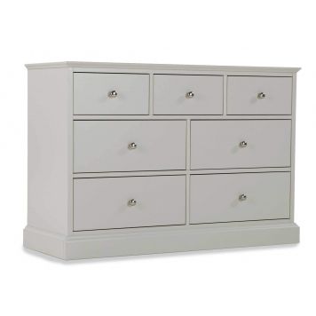 Angled shot of the Rivendale three over four grey chest of drawers with  small circular metal