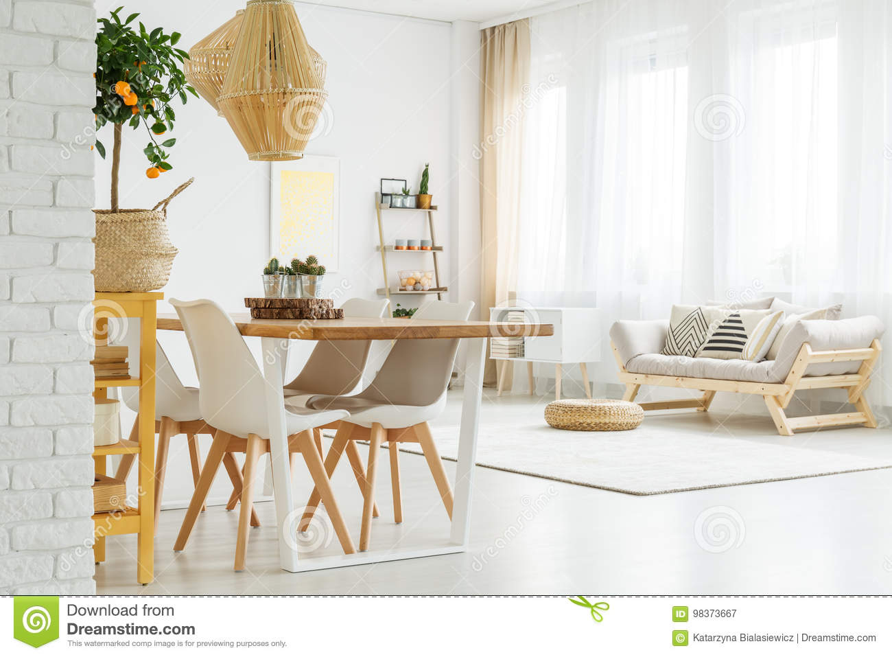 Open space with dinner table, white chairs and comfortable, grey sofa