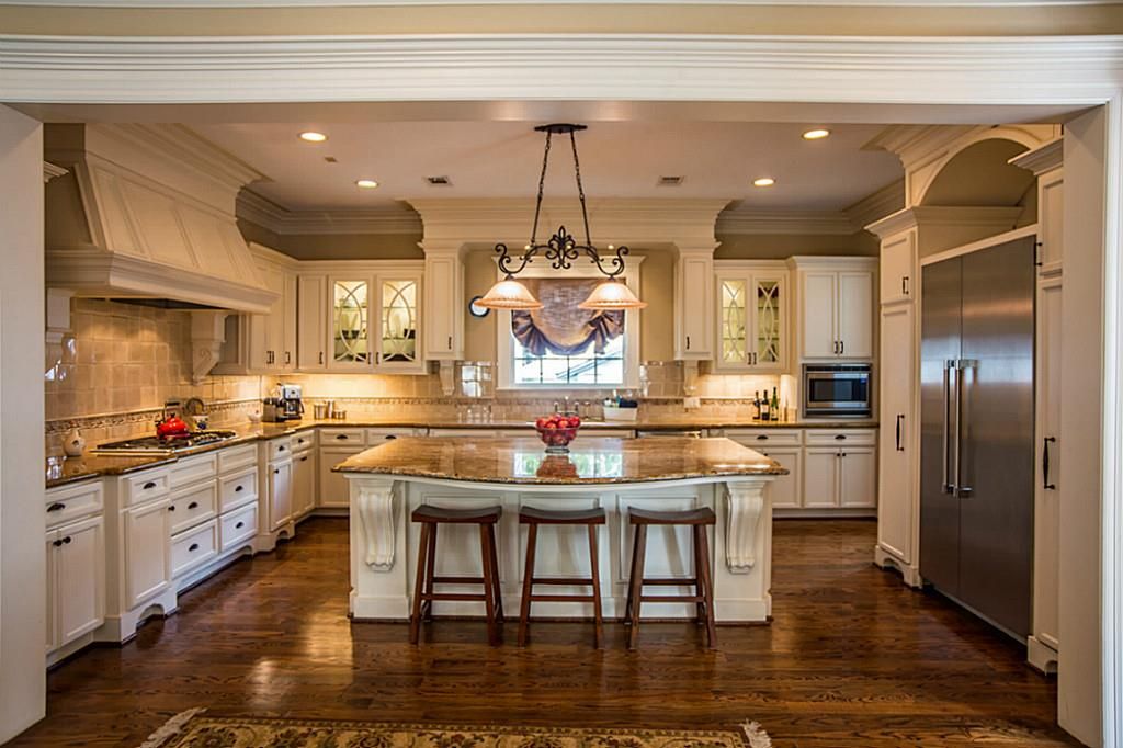 White traditional luxury kitchen with rich wood flooring inu-shape with  center island.