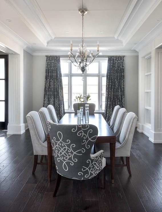 Gray dining room features a tray ceiling accented with a satin nickel and  glass chandelier illuminating a dark stained curved dining tab…