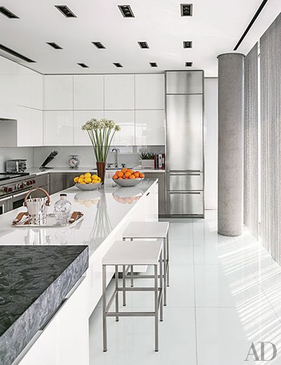 A Manhattan kitchen in a sleek building by Richard Meier has glamorous  shiny countertops of white