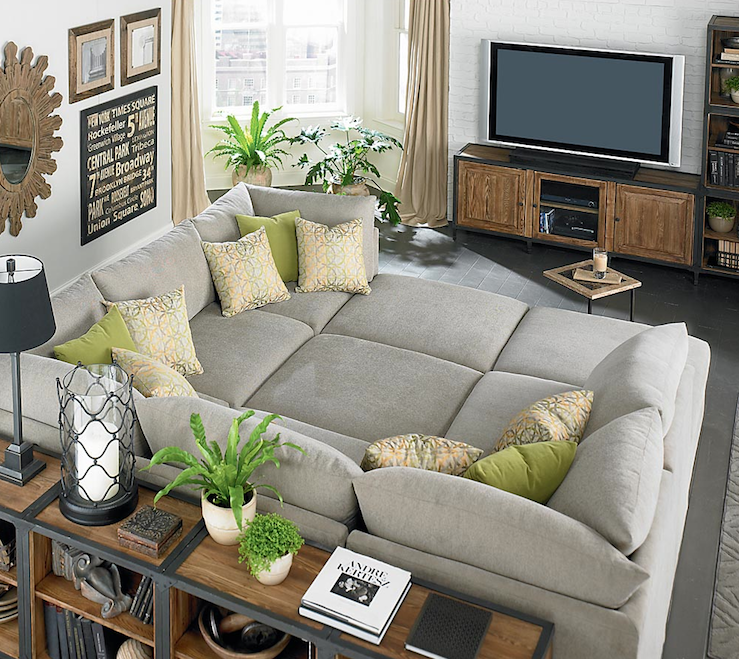 Huge gray Bassett Beckham Pit Sectional sofa, green pillows, industrial  bookshelves, subway sign, wood sunburst mirror, exposed brick wall painted  white and