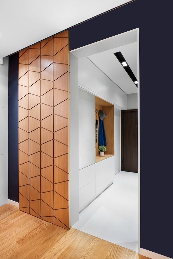 a modern plywood sliding door with a geometric pattern adds chic to the  space