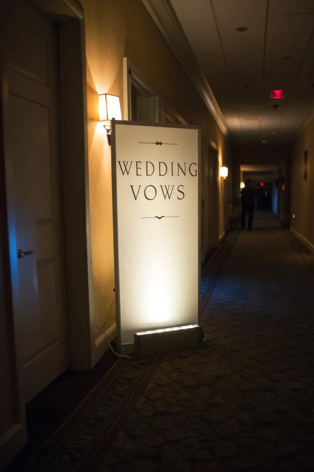Warmly glowing light box featuring wedding vows in a hallway.